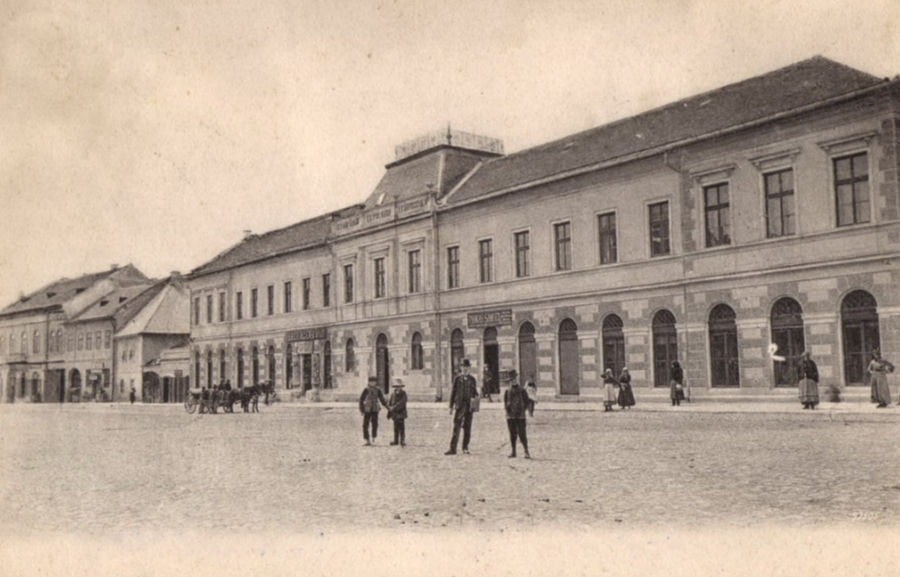 O fotografie istorică a Școlii Gimnaziale Ovidiu Hulea din Aiud cu oameni mergând în fața ei.